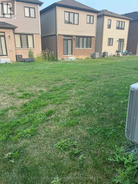 A grassy area in front of a row of houses with a large air conditioning unit in the foreground.