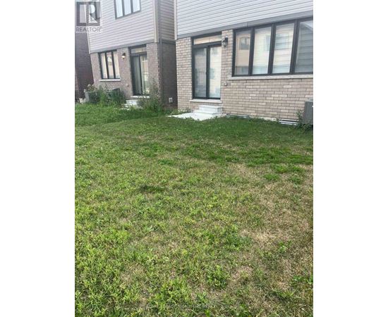 A grassy area in front of a brick building with a sign that says REALTOR.