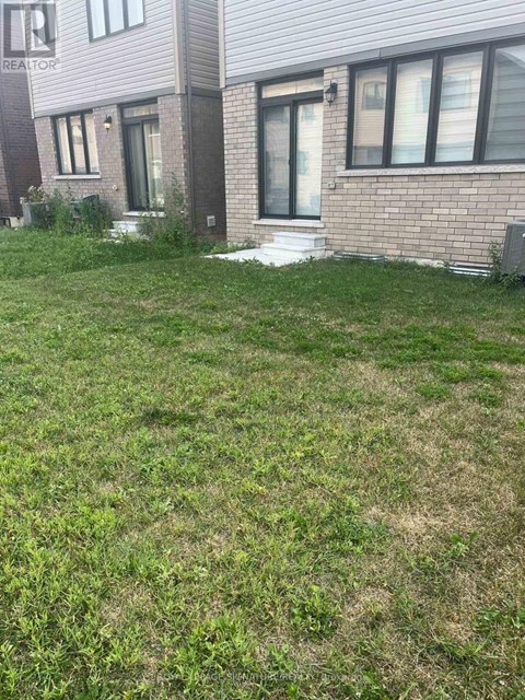 A grassy area in front of a brick building with a sign that says REALTOR.