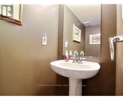 A white pedestal sink with a pink soap dish and a mirror above it.