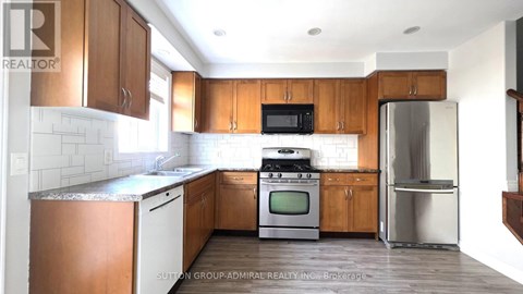 A kitchen with wooden cabinets and a stainless steel refrigerator.