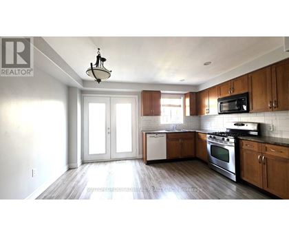 A kitchen with wooden cabinets and a black microwave.