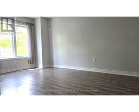 A room with wooden flooring and a window with white curtains.