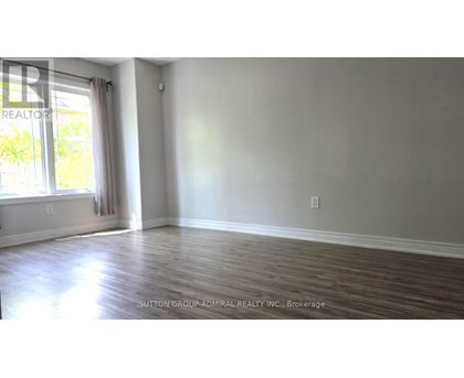 A room with wooden flooring and a window with white curtains.