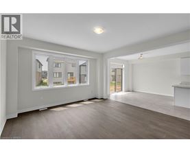 A spacious room with a large window showing a view of a house and a wooden floor.