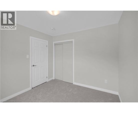 A bedroom with a white door and carpeted floor.
