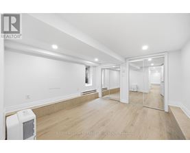 A spacious room with a white ceiling and wooden flooring.