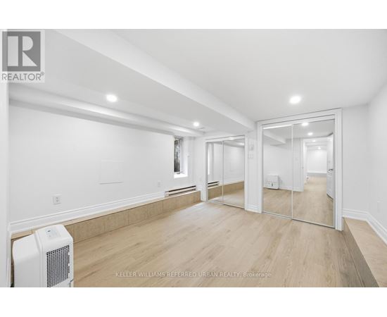 A spacious room with a white ceiling and wooden flooring.