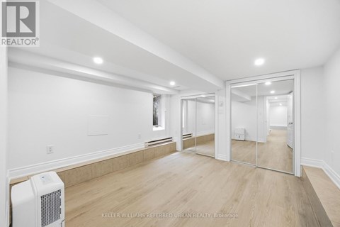 A spacious room with a white ceiling and wooden flooring.