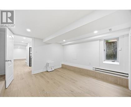 A spacious, empty room with a window and a door leading to another room.