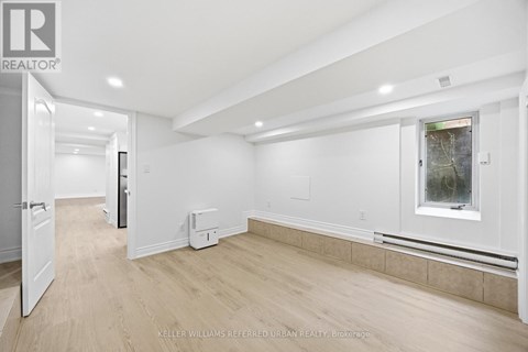 A spacious, empty room with a window and a door leading to another room.