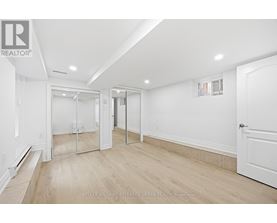 A spacious room with a white door and a mirror on the wall.