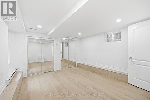 A spacious room with a white door and a mirror on the wall.