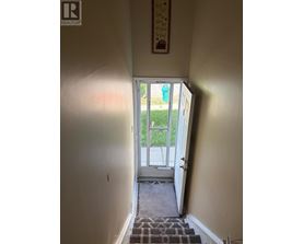 A hallway with a door leading to a balcony.