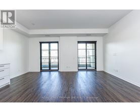 A spacious room with wooden floors and two windows with black frames.