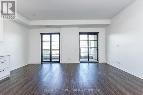 A spacious room with wooden floors and two windows with black frames.