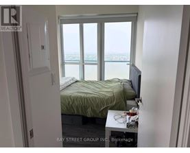 A bedroom with a bed, a window with a view, and a small table with a lamp on it.