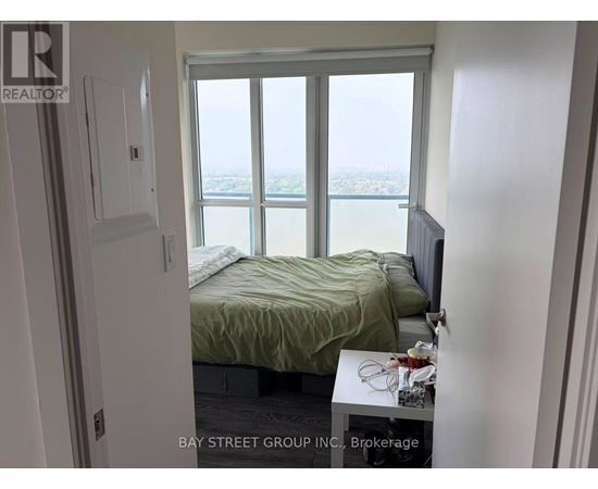 A bedroom with a bed, a window with a view, and a small table with a lamp on it.