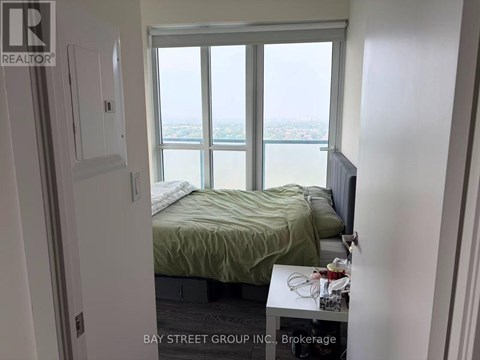 A bedroom with a bed, a window with a view, and a small table with a lamp on it.