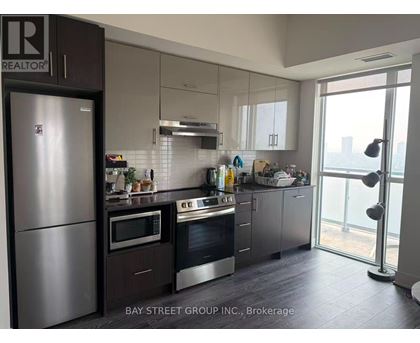 A modern kitchen with a refrigerator and stove top oven.