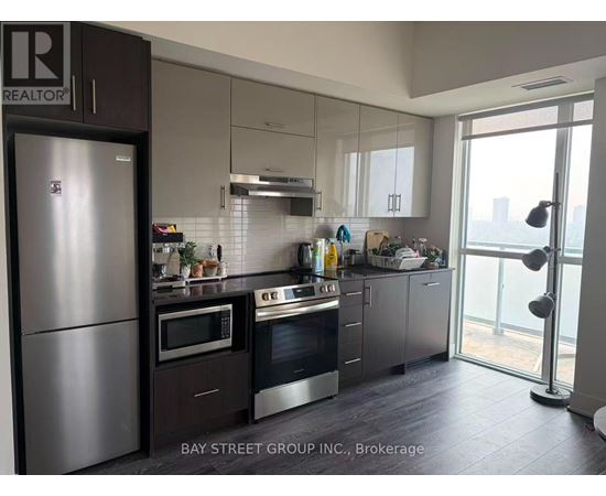 A modern kitchen with a refrigerator and stove top oven.