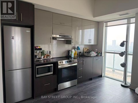 A modern kitchen with a refrigerator and stove top oven.