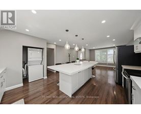 A modern kitchen with white cabinets and a wooden floor.