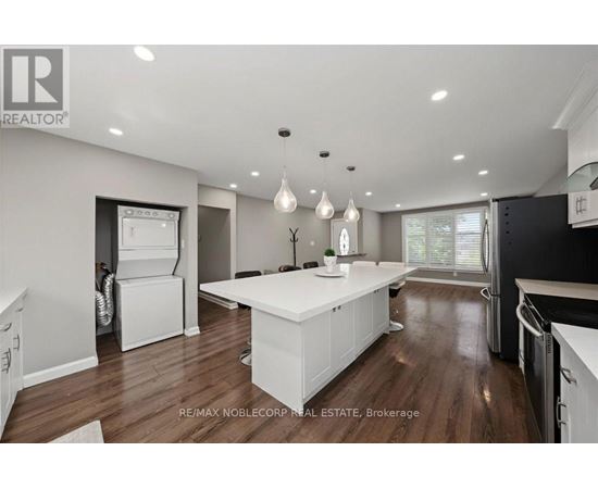 A modern kitchen with white cabinets and a wooden floor.