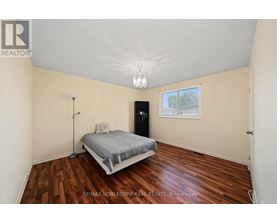 A bedroom with a bed, nightstand, and a window.