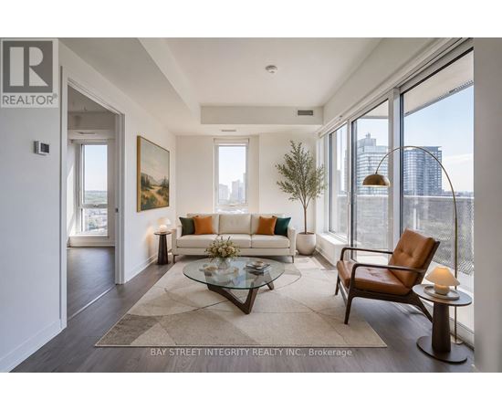 A living room with a couch, a chair, a coffee table, and a painting on the wall.