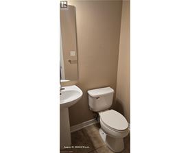 A white toilet in a bathroom with a sink and a door.