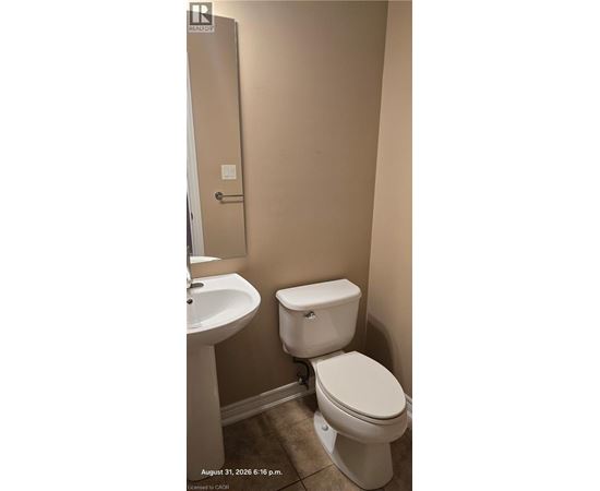 A white toilet in a bathroom with a sink and a door.