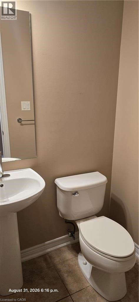 A white toilet in a bathroom with a sink and a door.