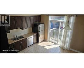 A kitchen with a sink, refrigerator and a window.