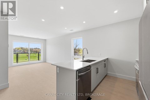 A spacious kitchen with a dishwasher and a window overlooking a green field.