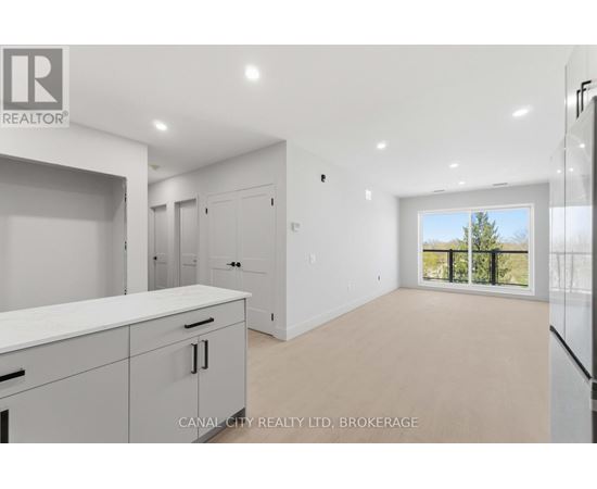 A spacious room with a kitchen area and a view of the outdoors through a sliding glass door.
