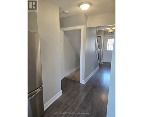 A kitchen with a stainless steel refrigerator and wooden flooring.