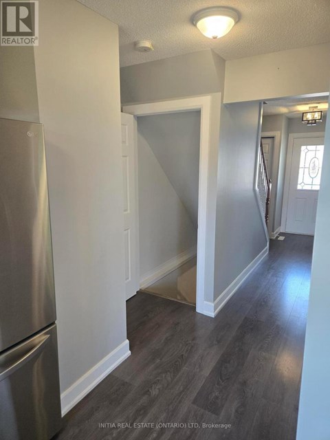 A kitchen with a stainless steel refrigerator and wooden flooring.