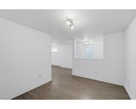 A spacious room with wooden flooring and a window.