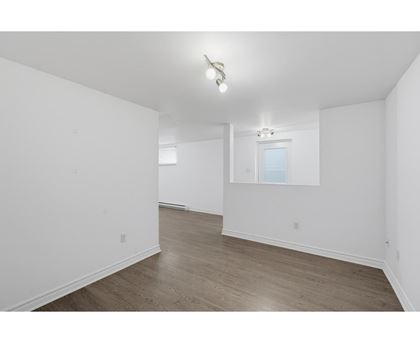 A spacious room with wooden flooring and a window.