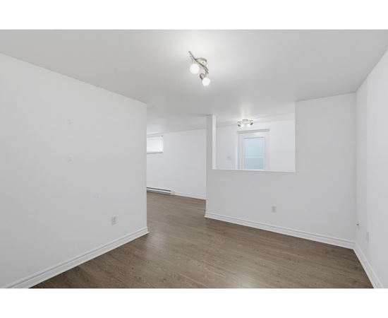 A spacious room with wooden flooring and a window.