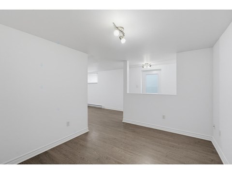 A spacious room with wooden flooring and a window.