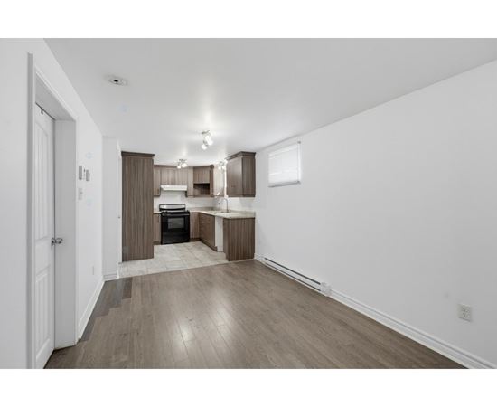 A kitchen with white walls and wooden floors.