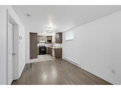 A kitchen with white walls and wooden floors.
