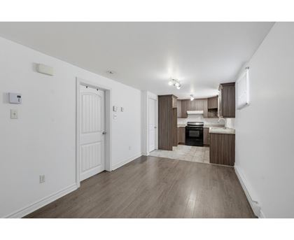 A kitchen with white walls and wooden floors.