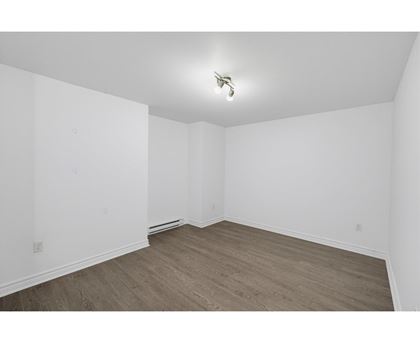 A room with wooden flooring and white walls.