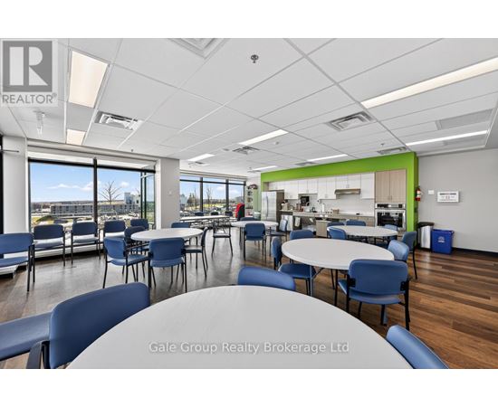 A conference room with a table and chairs in the foreground and a kitchen area in the background.