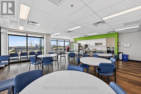 A conference room with a table and chairs in the foreground and a kitchen area in the background.