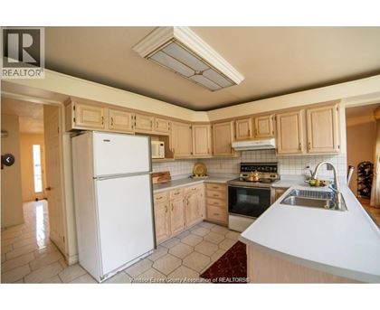 A kitchen with a white refrigerator and wooden cabinets.