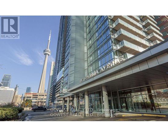 A building with a glass facade and a tall tower in the background.